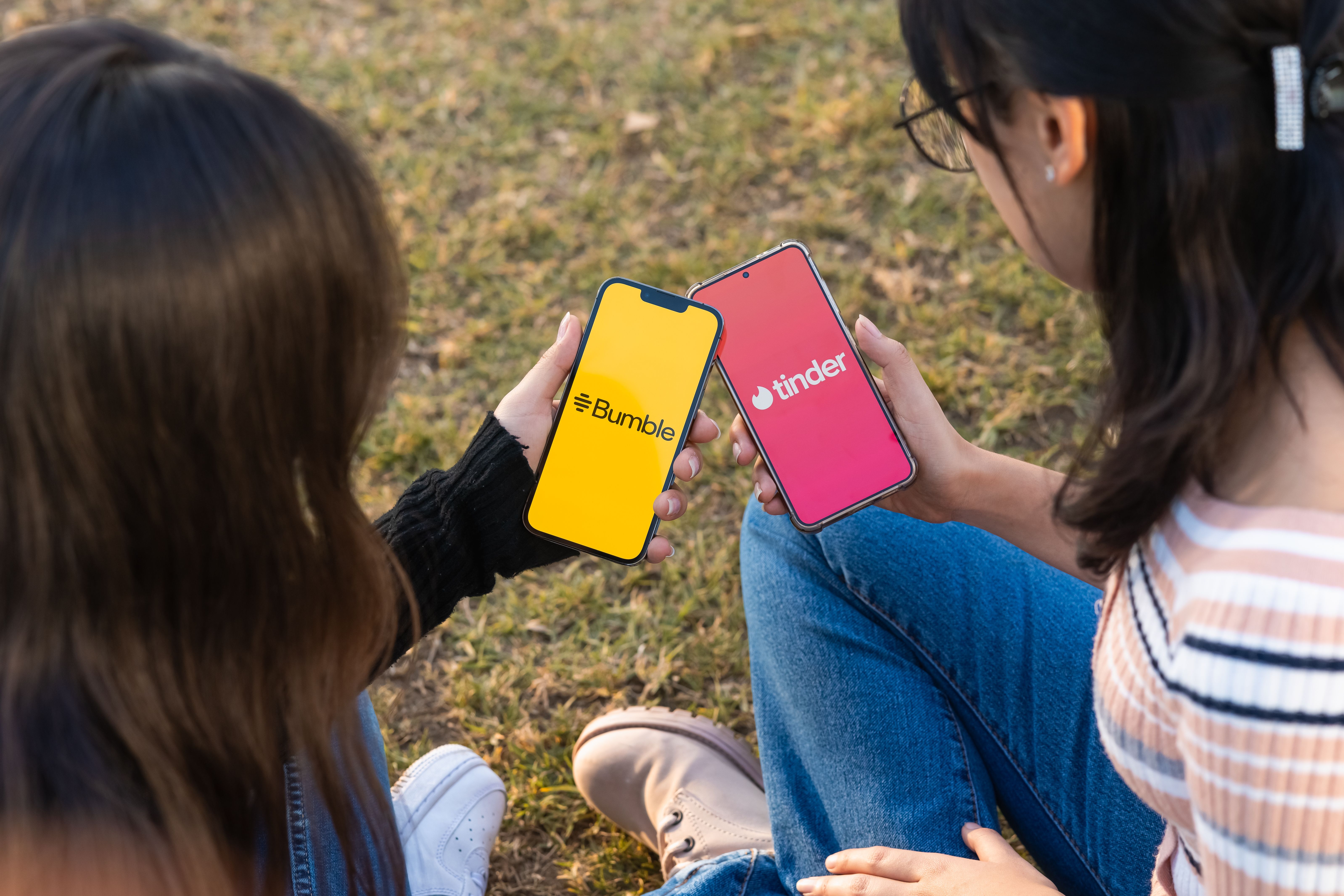Two women using dating apps on their smartphones outdoors